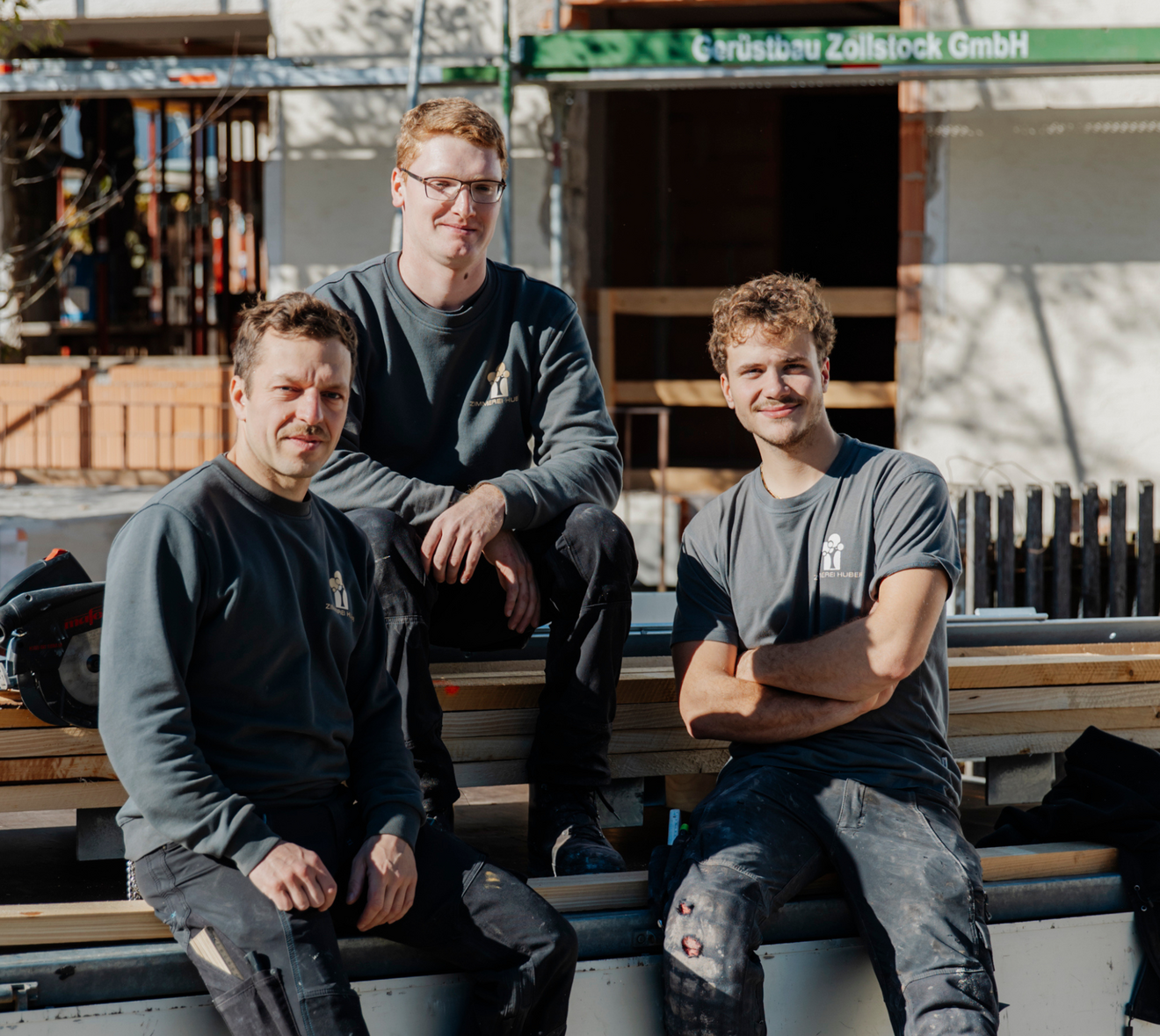 Das Team der Zimmerei Huber auf einem Hänger mit Holz sitzend.
