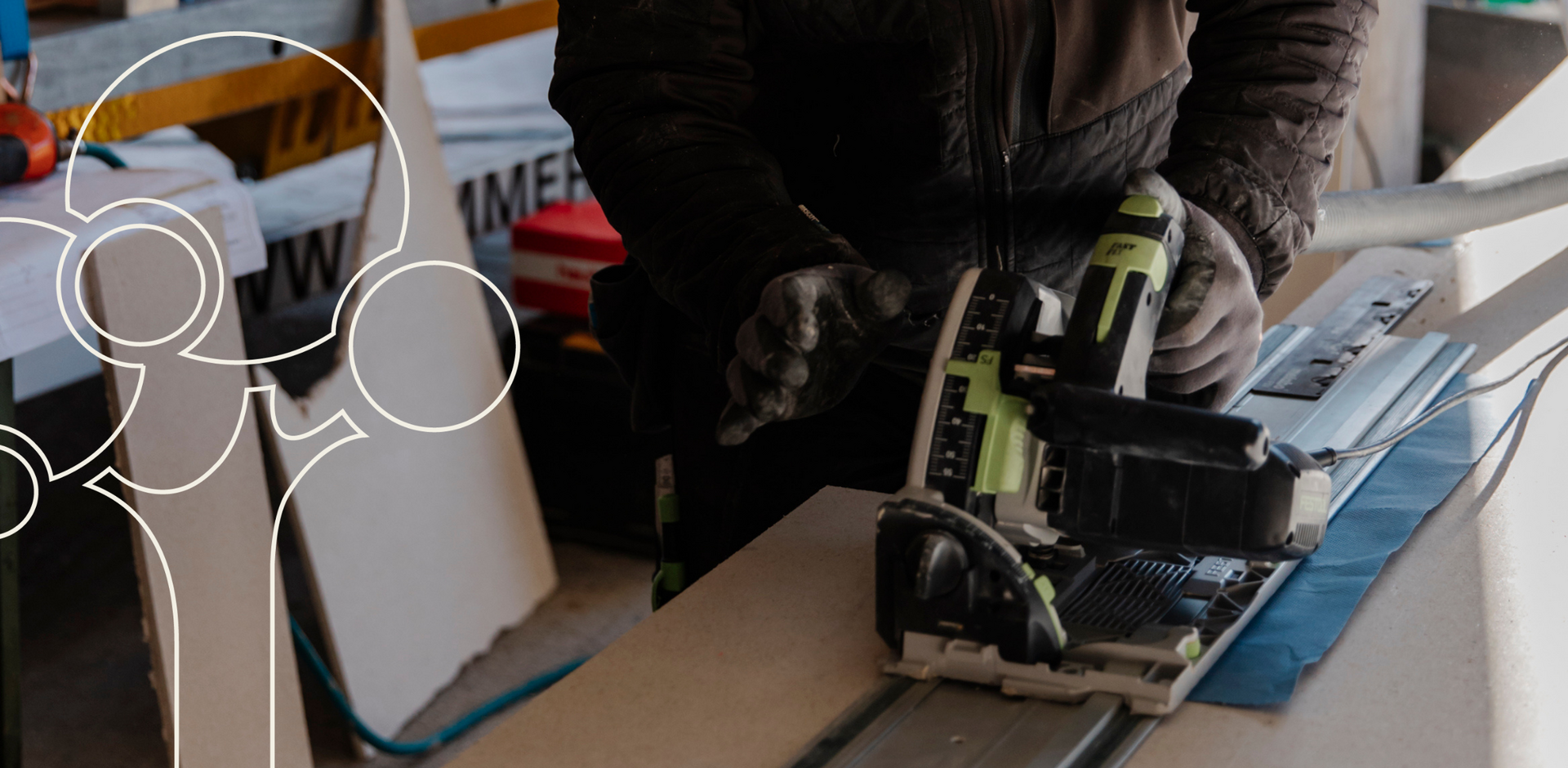 Die behandschuhten Hände eines Zimmerei-Mitarbeiters halten eine Schleifmaschine.